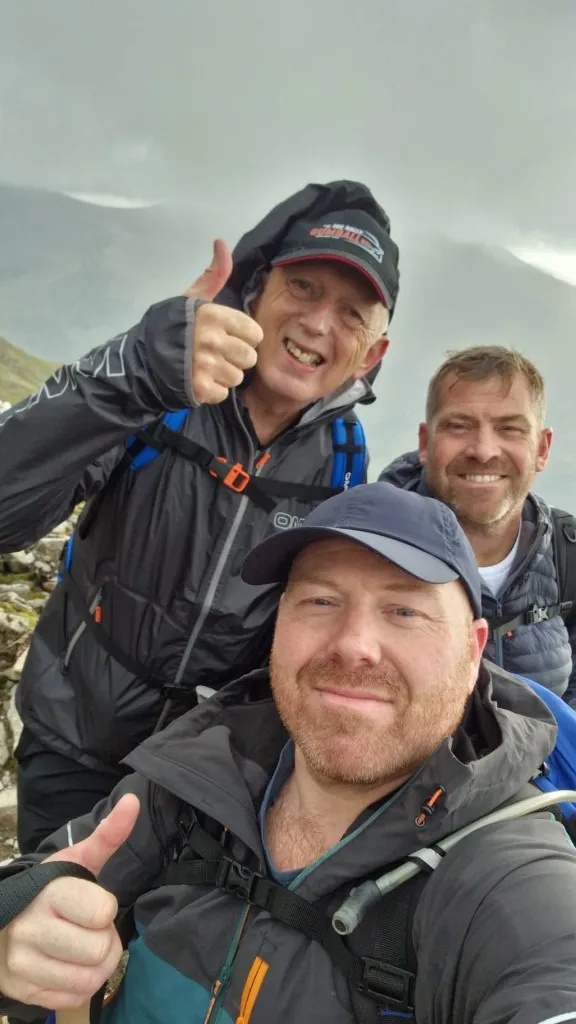 Three members of the challenge team smiling and giving a thumbs up on the mountain