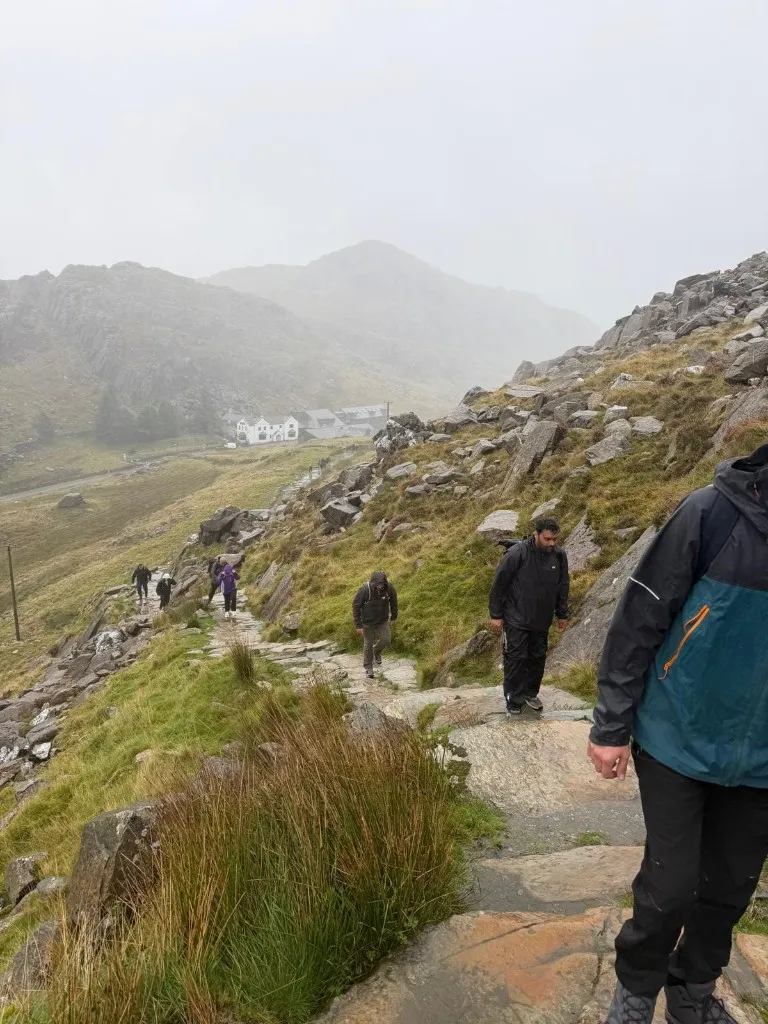 Challenge participants climbing the rocky path on Snowdon in misty conditions