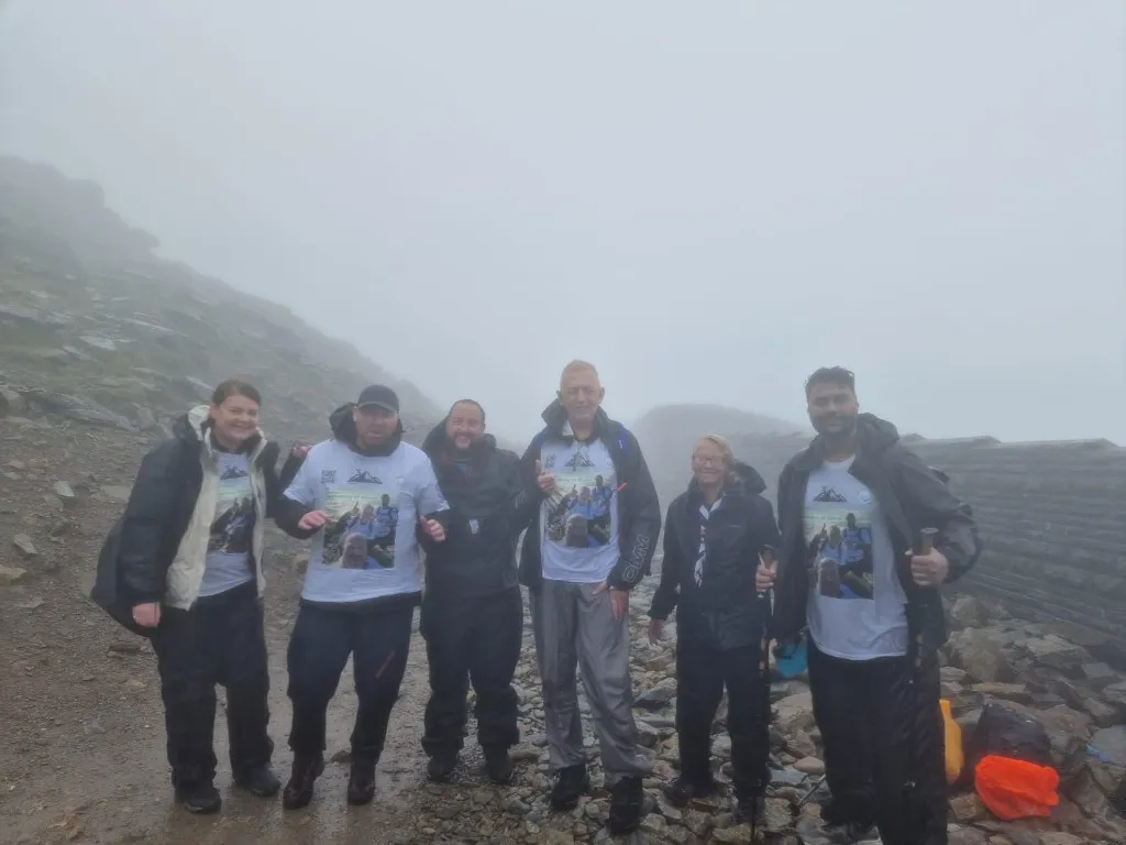 Challenge participants wearing Kieran memorial fundraising shirts in wet mountain weather