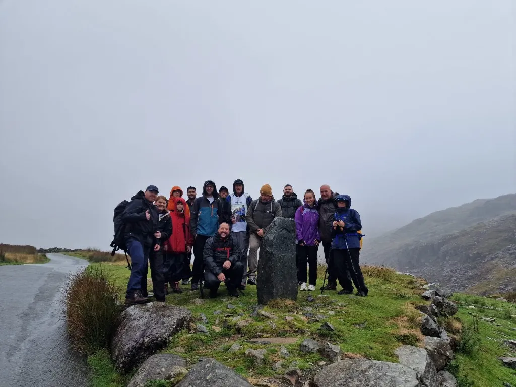 Mantech team gathered beside a mountain marker during the Three Peaks Challenge